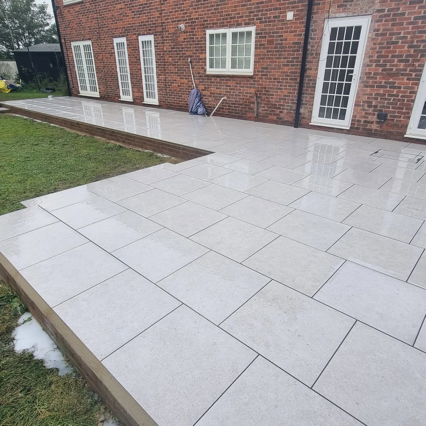 Light grey porcelain patio along a brick house