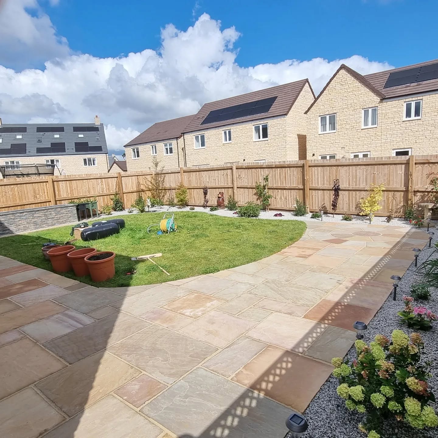 Curved sandstone patio and paths round a lawn in a new-build garden