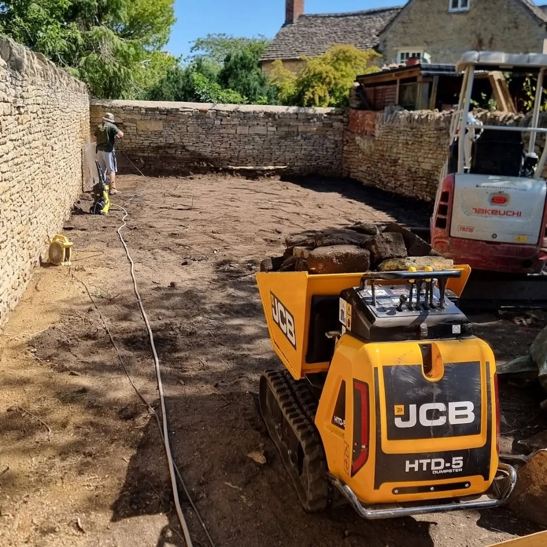 Tracked dumper and mini digger at work in a stone-walled garden