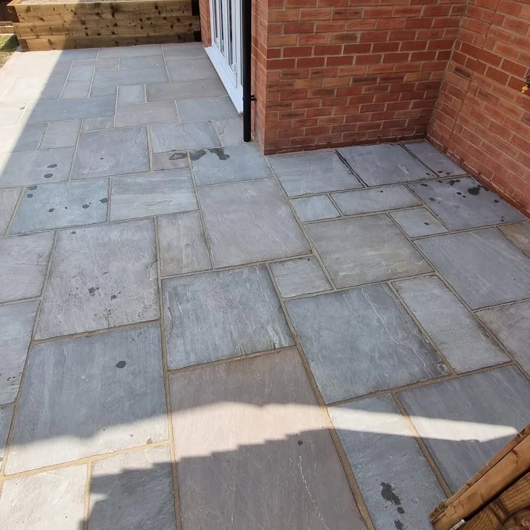 Grey sandstone patio next to a red-brick house