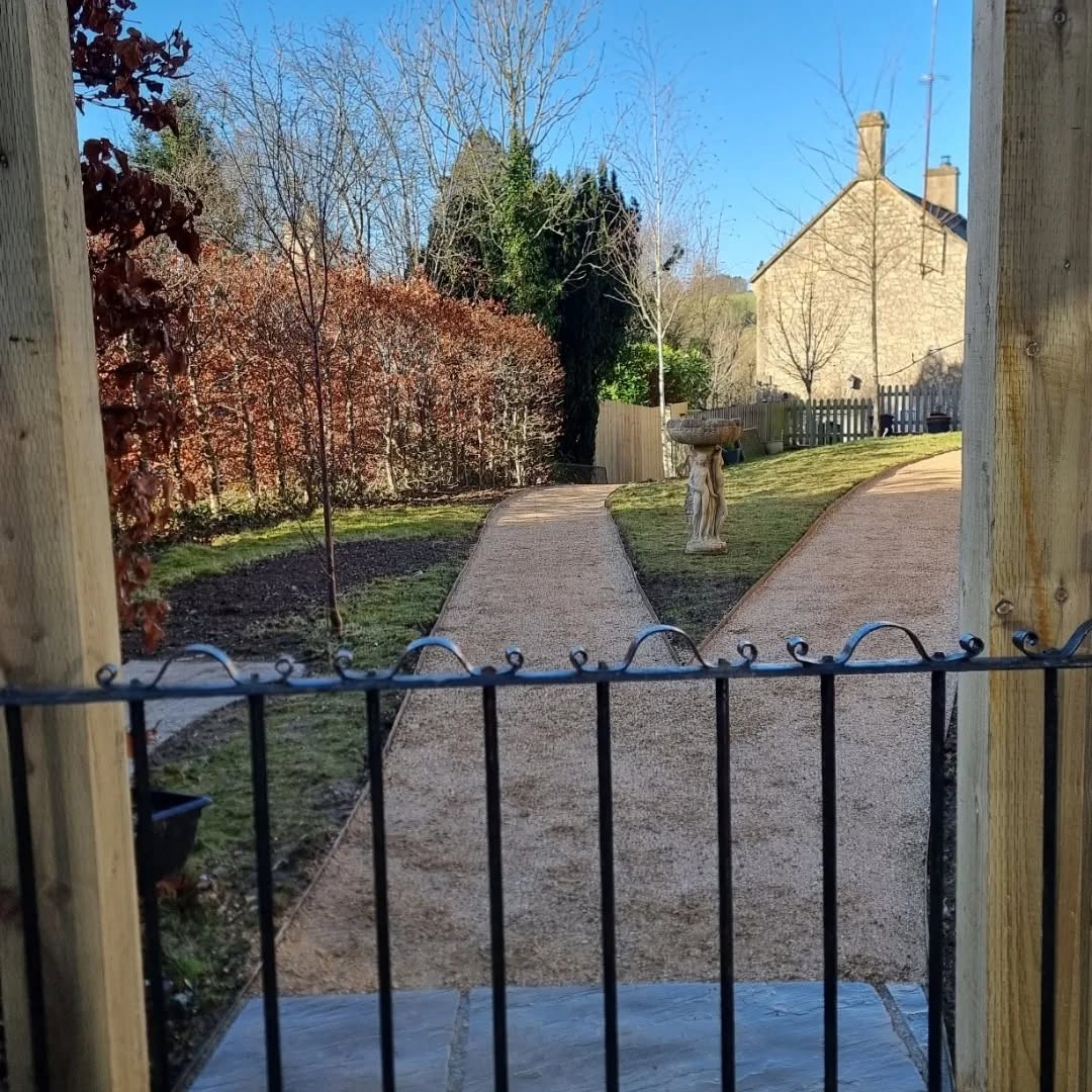 Gravel paths through a garden, seen through an iron gate