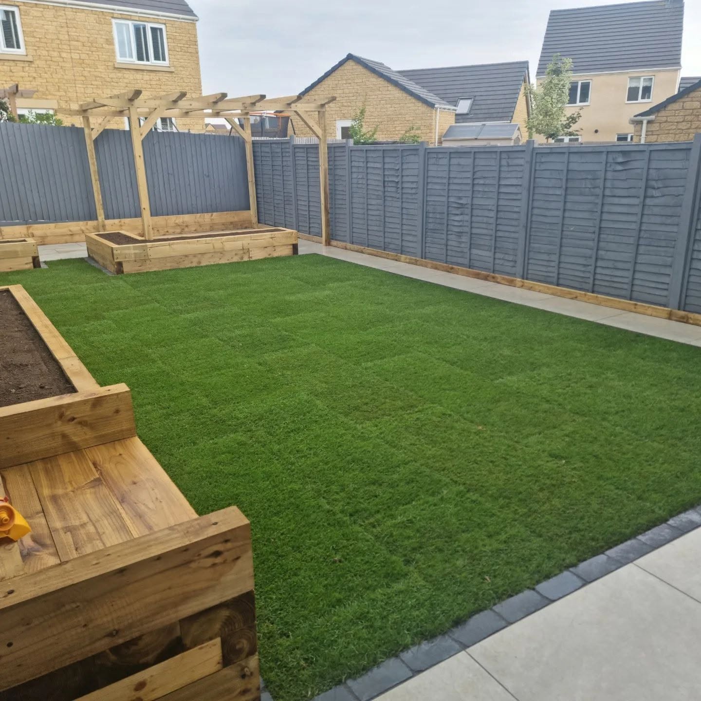 New lawn framed by timber sleeper beds in a new-build garden