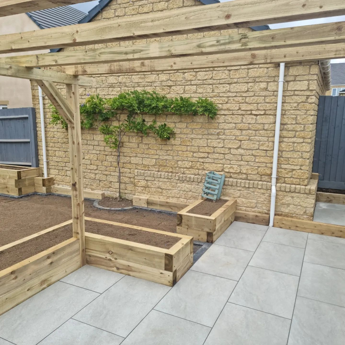 Timber pergola over a porcelain patio with sleeper planters