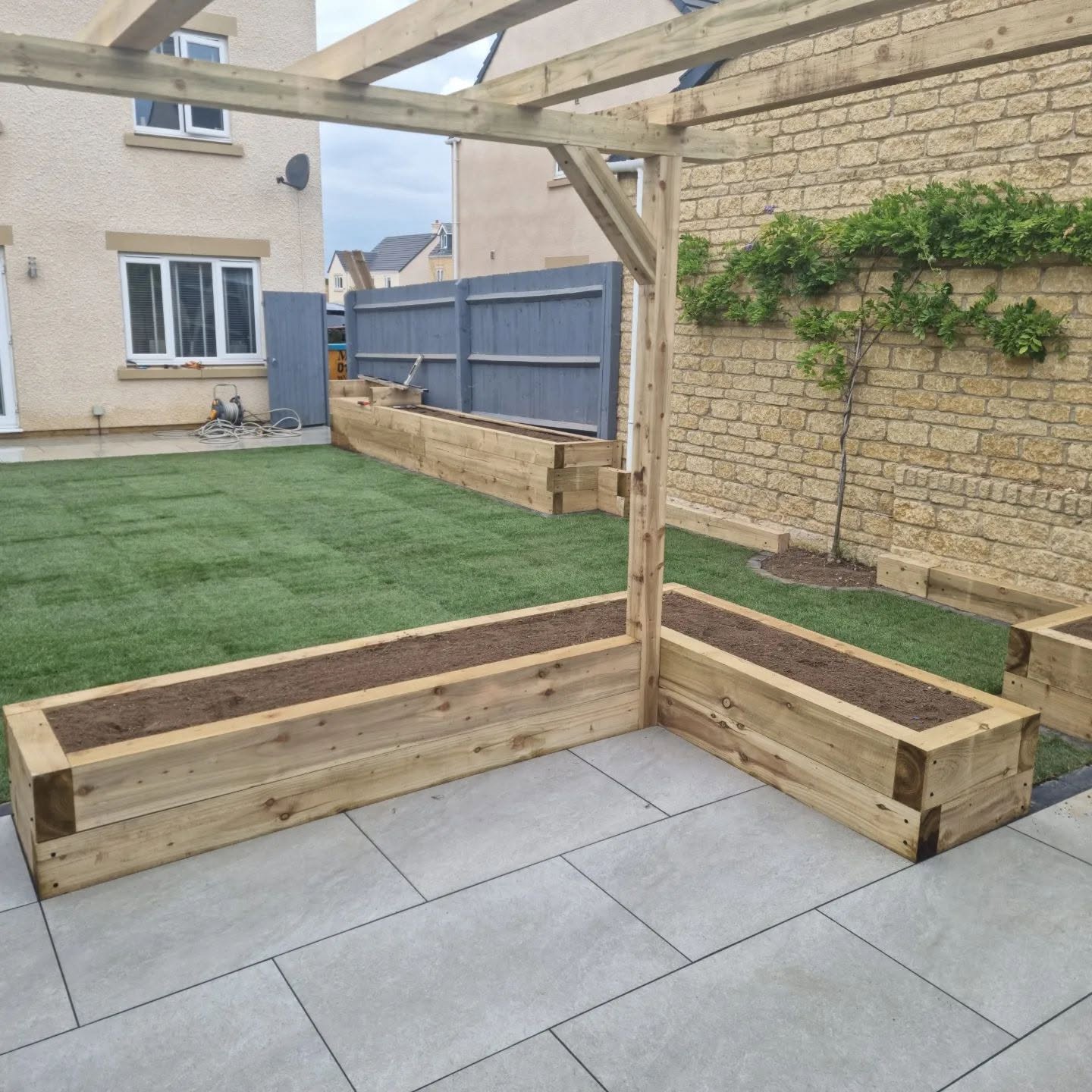Finished pergola corner with sleeper beds, patio and lawn