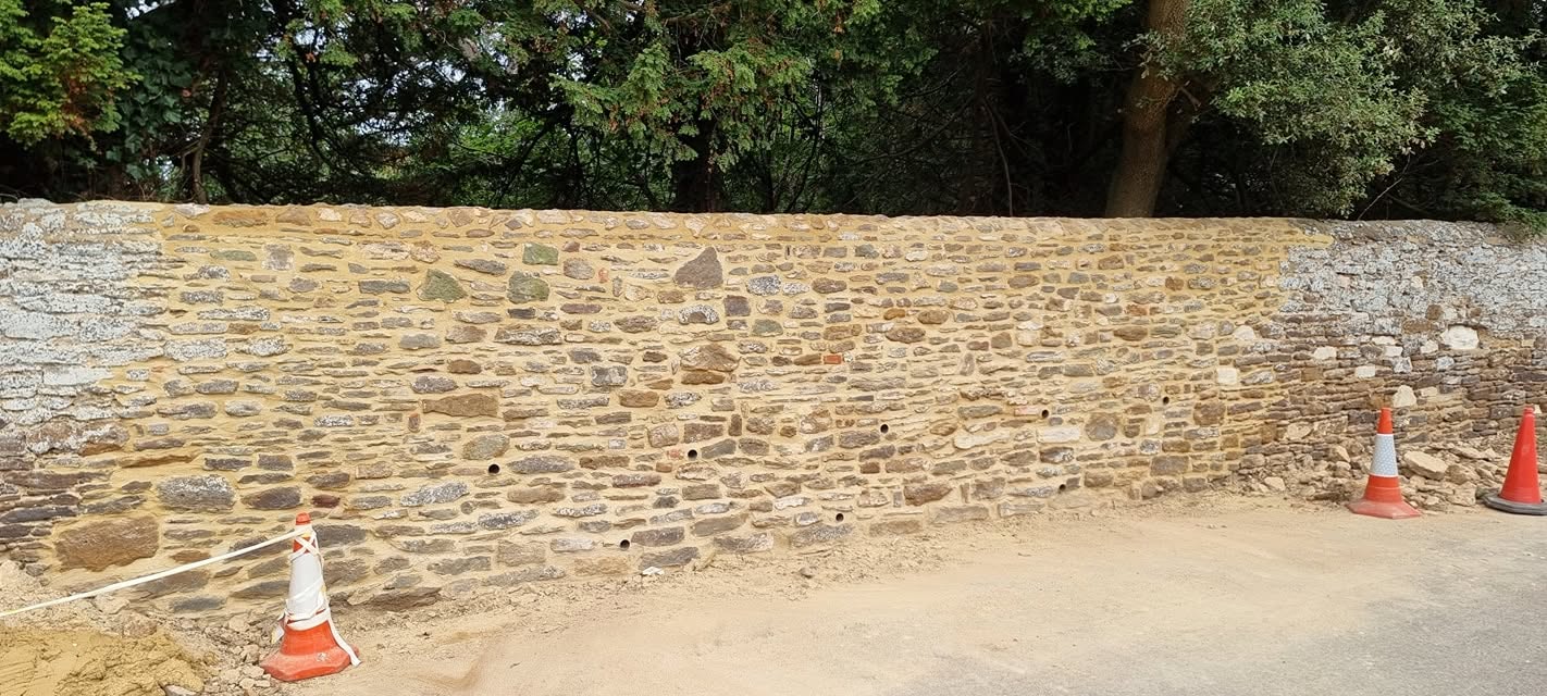 Long roadside stone wall with cones beside it