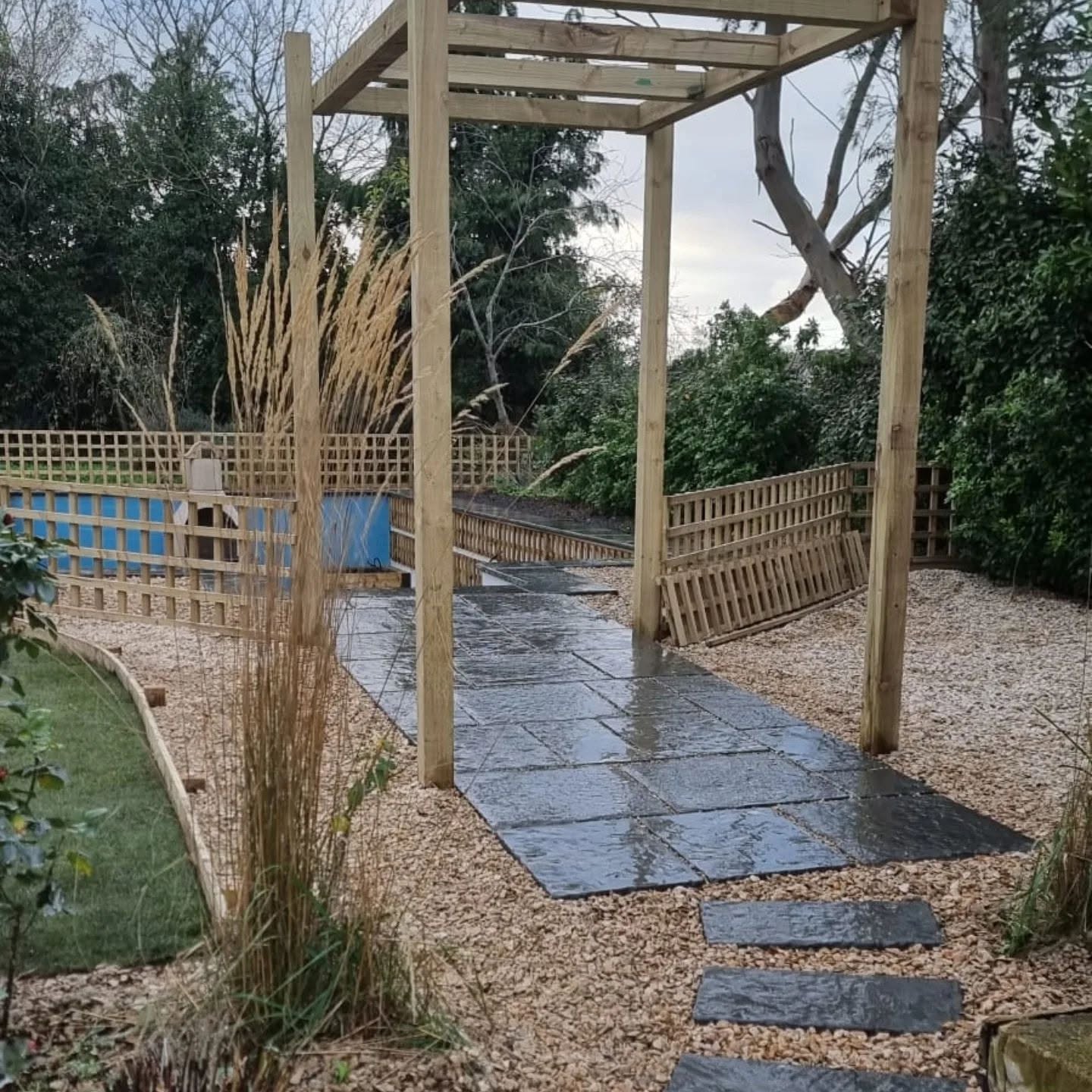 Timber pergola over a slate path with stepping stones and gravel