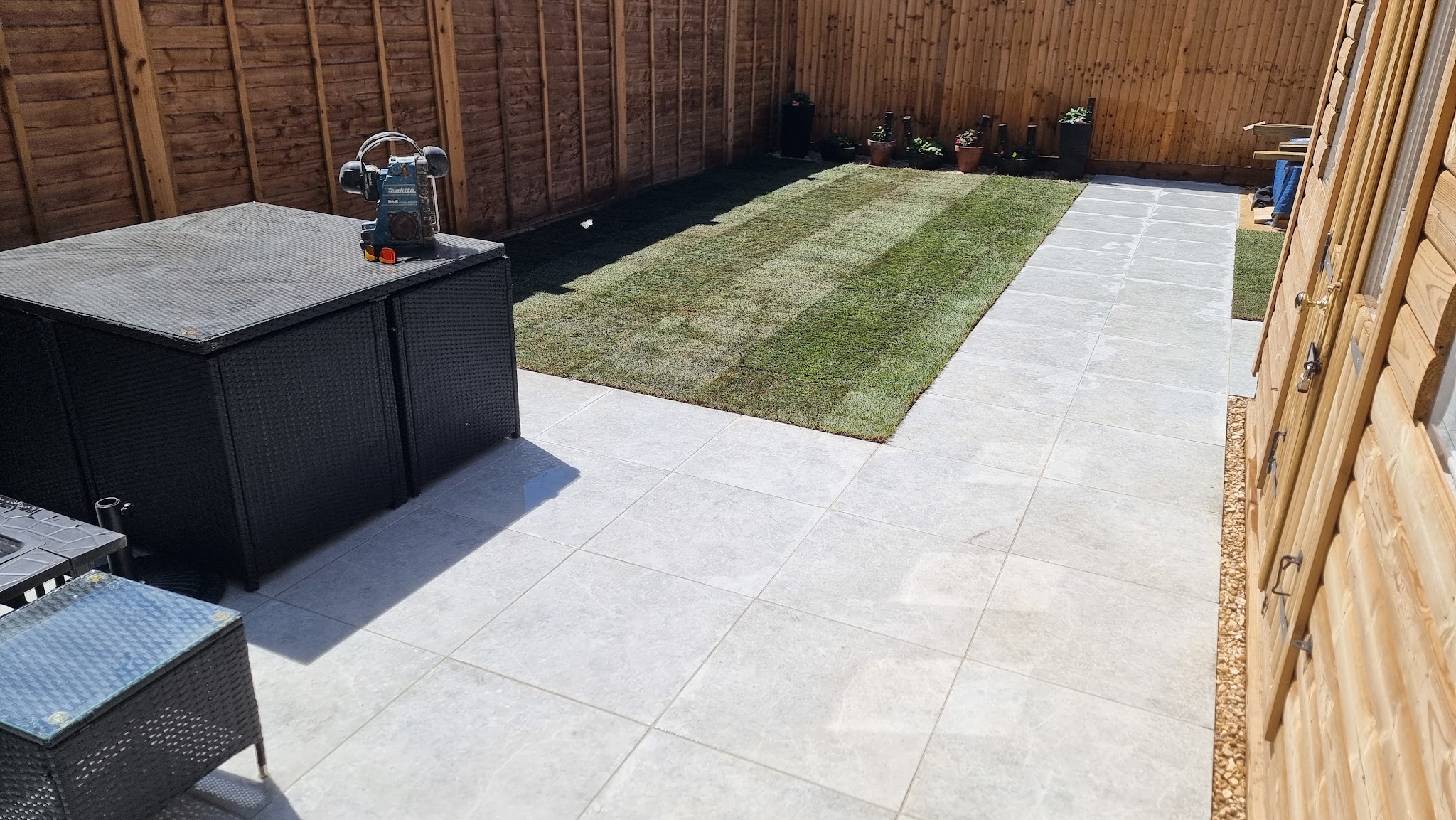 Light grey porcelain patio and path beside fresh turf and a new fence