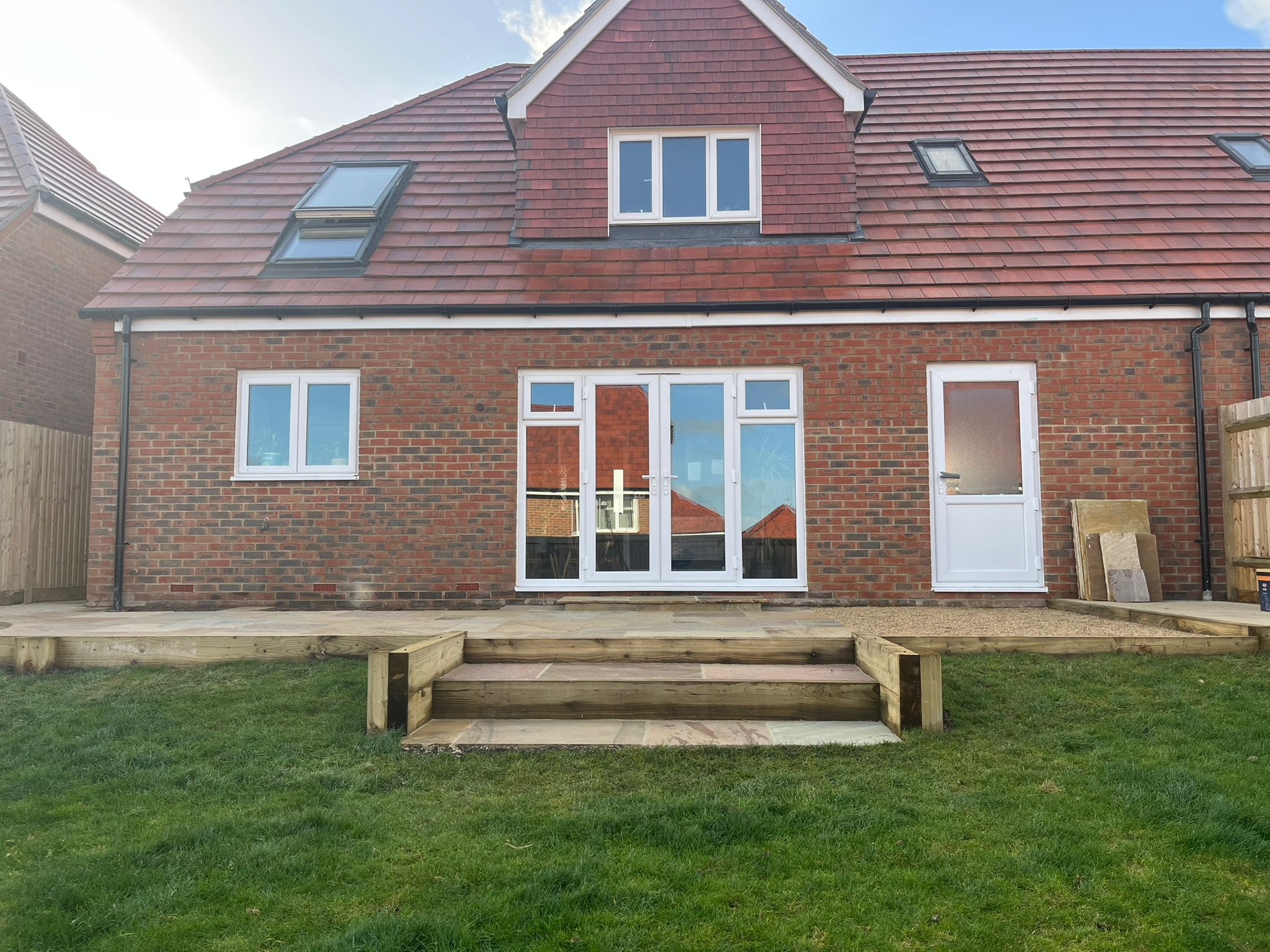 Timber deck with sleeper steps across the back of a brick house